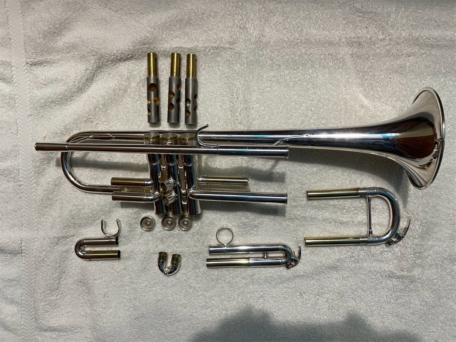 Cleaned and detarnished Yamaha intermediate trumpet, disassembled laying on floor.