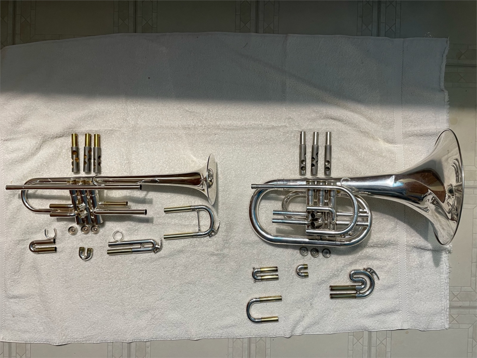 Trumpet and mellophone, disassembled laying on the floor together.